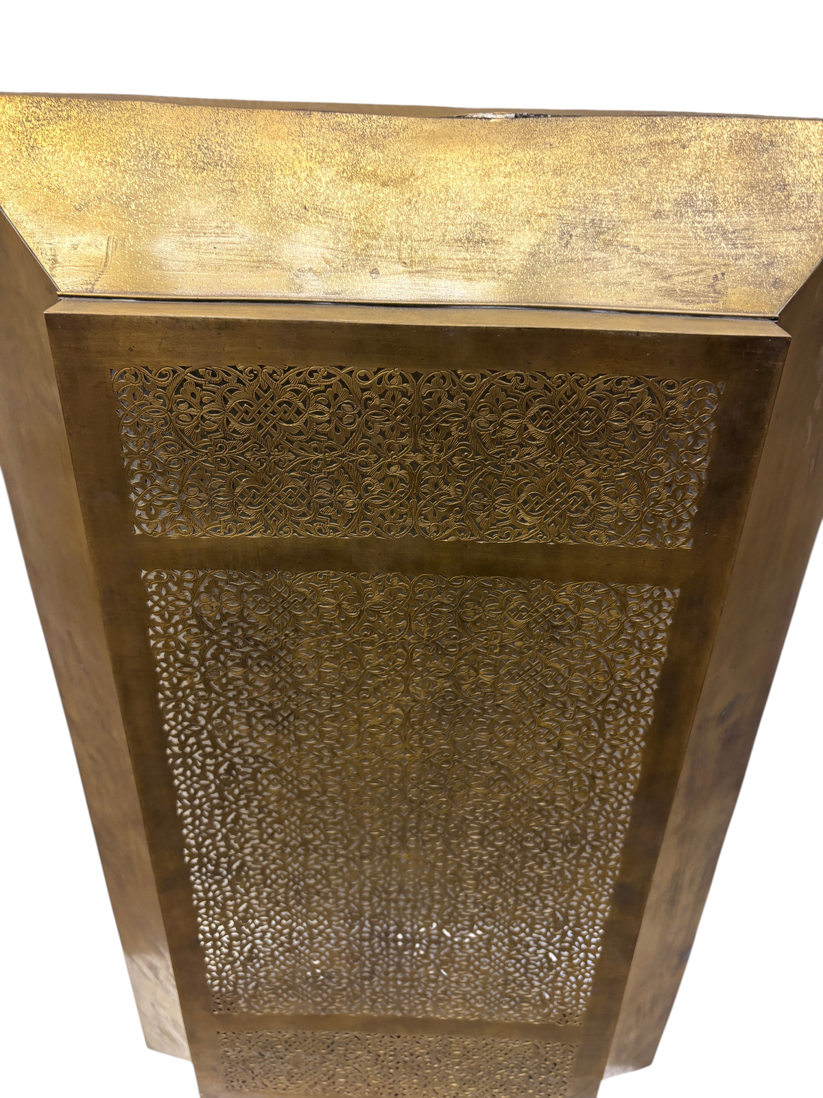 A tall, golden hexagonal planter features intricate, perforated arabesque patterns along its side.