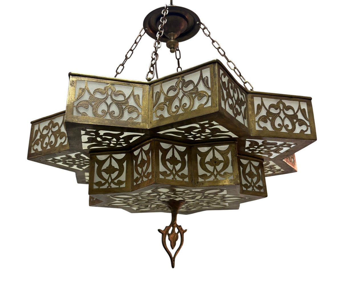 An ornate multi-tiered geometric chandelier with intricate cutout metalwork and white glass panels, suspended by chains against a plain white background.