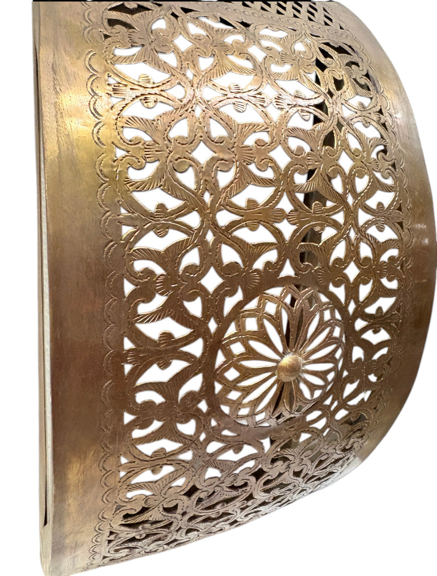 A close-up of a brass wall sconce with intricate filigree patterns, showcasing its warm metallic finish and detailed craftsmanship.