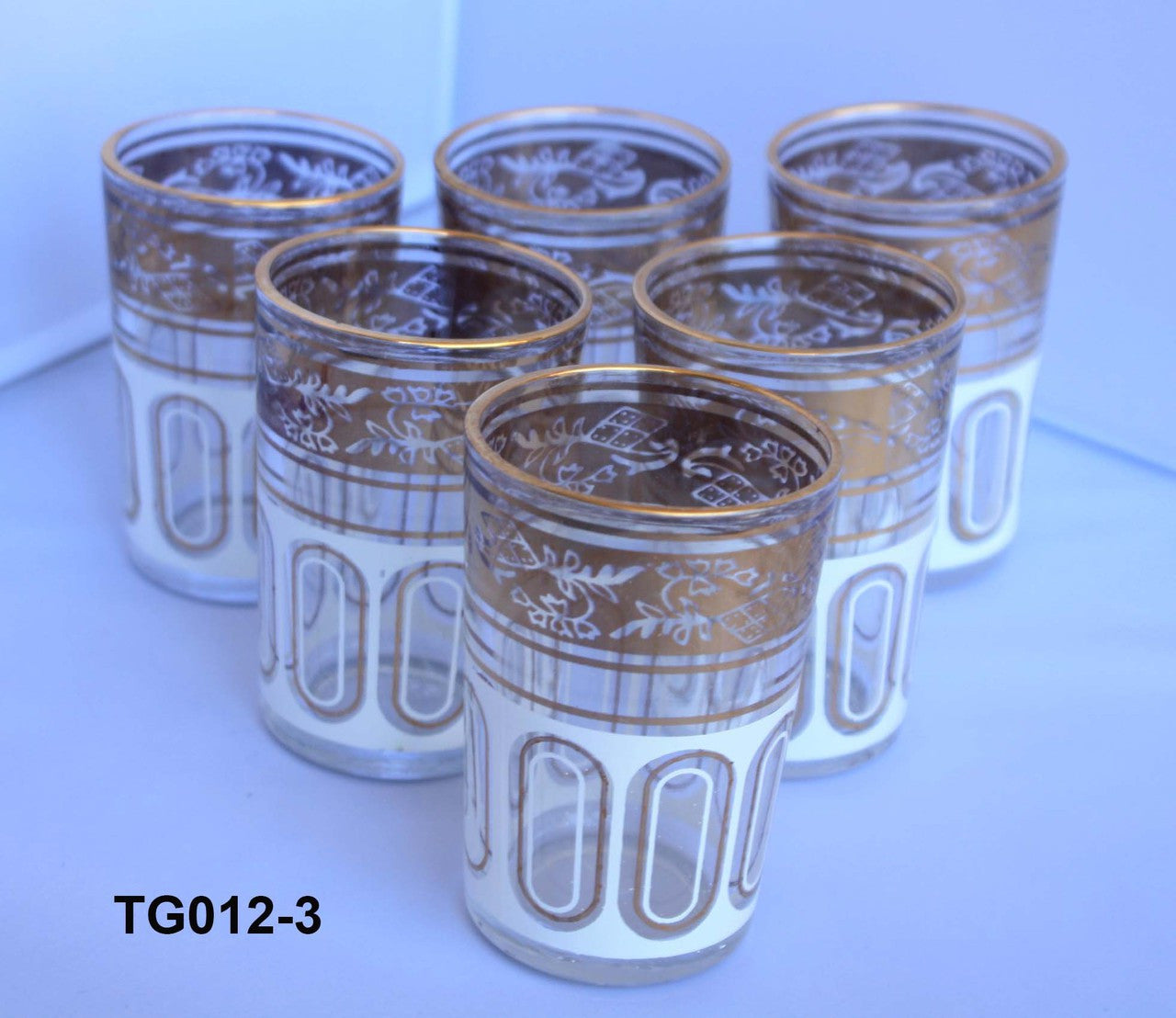 Set of six glasses with gold patterns on a white surface