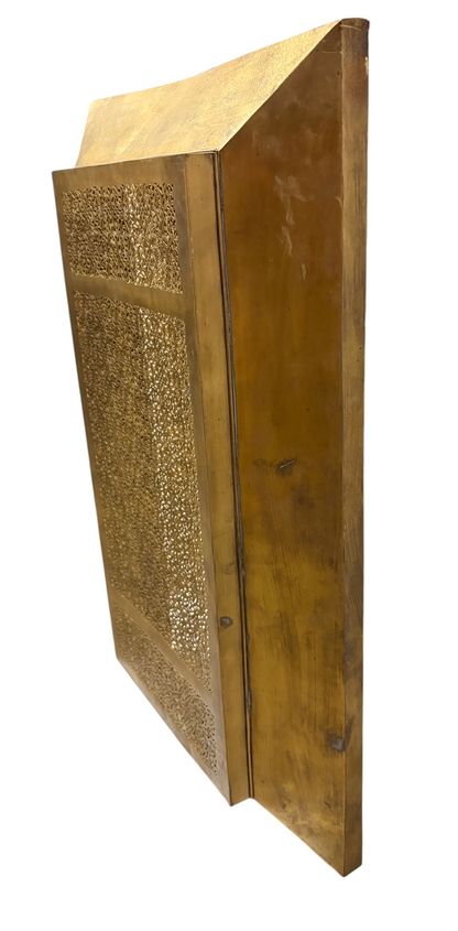 A tall, rectangular brass radiator cover with an ornate perforated metal grille stands upright against a plain white background.