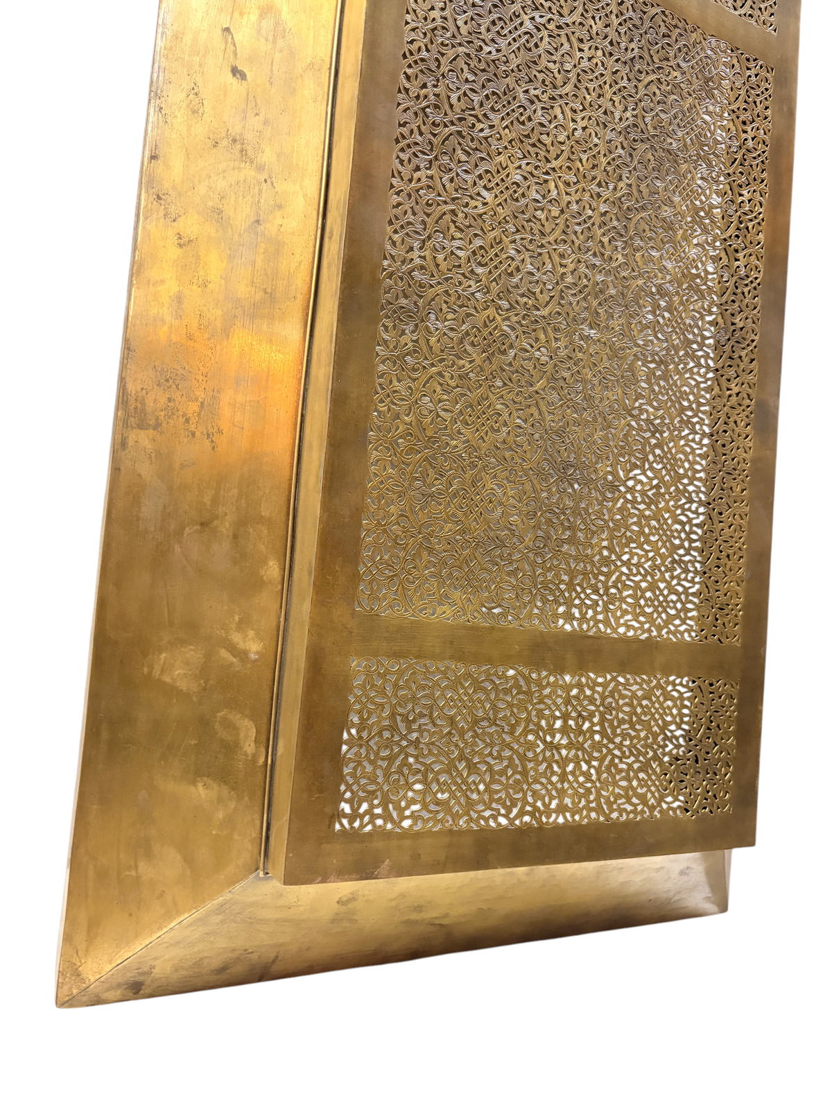 A polished brass radiator cover features intricate geometric and floral laser-cut patterns.