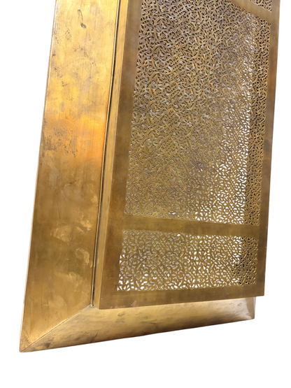 A polished brass radiator cover features intricate geometric and floral laser-cut patterns.