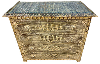A distressed vintage-style wooden chest with a weathered brown and gold finish, featuring carved geometric diamond patterns and ornate gold-toned handles on the front, set against a plain white background.