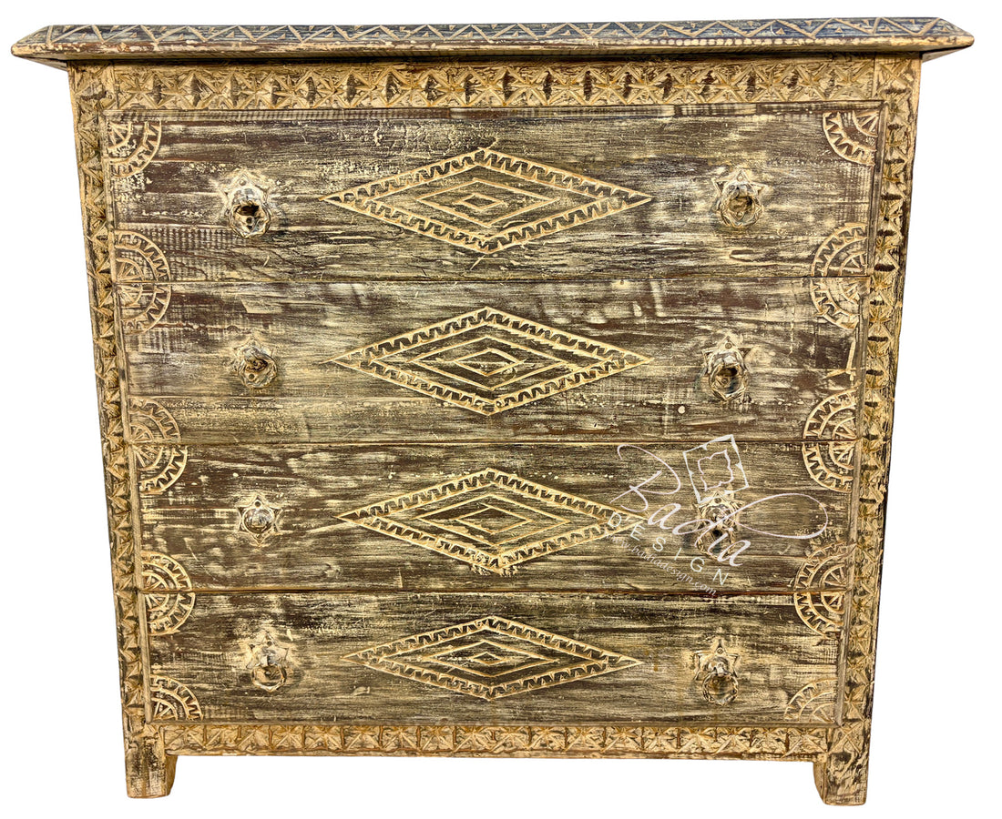 A distressed wooden chest of drawers with a weathered brown and beige finish, decorated with gold-toned geometric patterns and ornate drawer pulls.