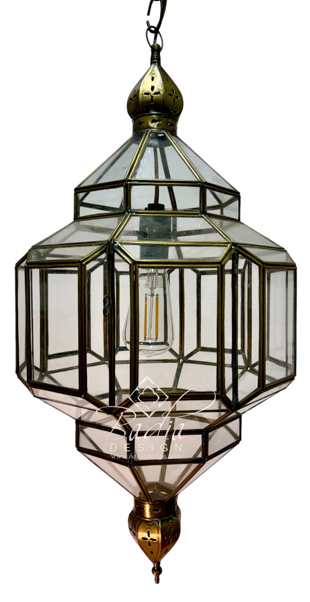 A hanging lantern-style pendant light with a brass or bronze metal frame and clear glass panels, shown against a plain white background. A bulb is visible inside, and a watermark/logo appears near the lower center.