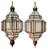 Two matching geometric hanging lantern-style pendant lights with clear glass panels and brass/gold-toned metal framing, shown side by side on a white background.