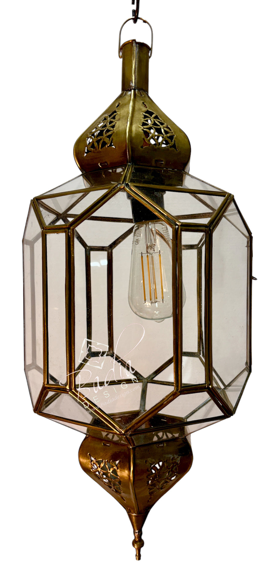 An ornate brass hanging lantern with clear glass panels and a visible filament light bulb, isolated on a white background.
