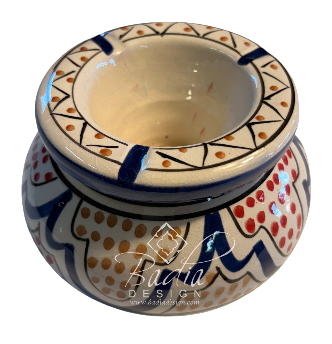 A hand-painted ceramic candle holder with a wide rim and a rounded base, decorated with blue, red, and orange patterns on a cream background. A &