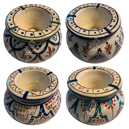Four ceramic candle holders arranged in a 2x2 grid, each shown from a different angle. The holders have a warm cream base with hand-painted geometric and tribal patterns in navy blue, red, green, and orange.