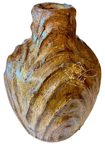 A rustic, organic-shaped ceramic vase with a highly textured, sculpted surface resembling polished wood or stone. It features a rich color palette of earthy brown, golden-brown, and amber tones with subtle iridescent blue-green highlights on the left side, set against a plain white background.