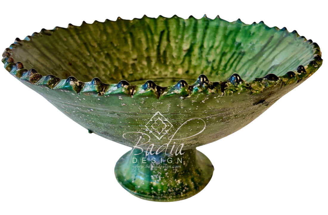 A green ceramic pedestal bowl with a textured, ribbed interior and a flared, scalloped rim, shown on a plain white background with a &