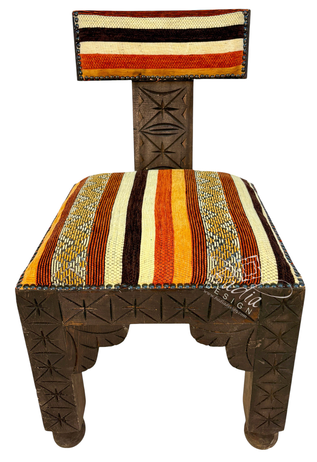 A carved wooden chair with a striped woven seat and backrest, featuring geometric patterns on the wooden frame and colorful stripes in orange, yellow, cream, and brown.