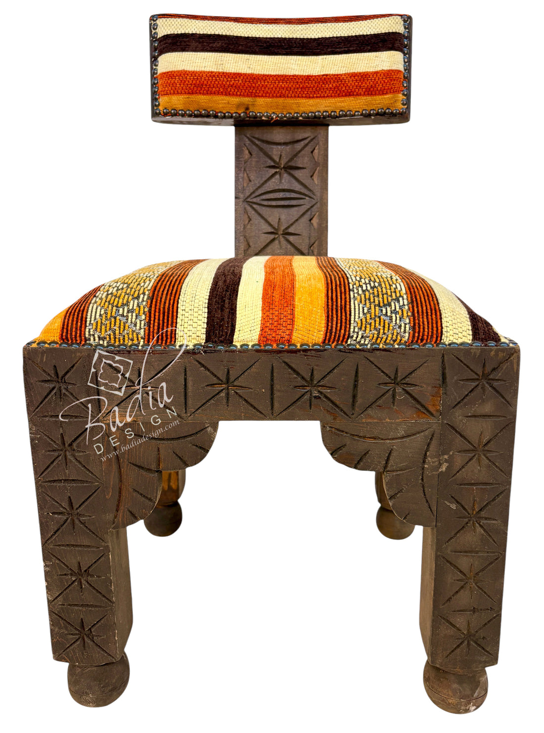A traditional carved wooden stool with a striped upholstered seat and backrest, featuring geometric star patterns on the legs and a colorful striped textile design.