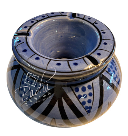 A handmade ceramic pot with a glossy blue and black hand-painted geometric pattern, featuring a wide rim with small cutouts and a wide base, shown on a white background with a &