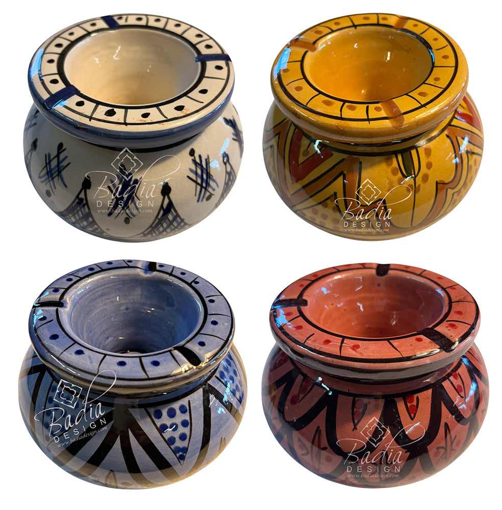 Four hand-painted ceramic candle holders arranged in a 2x2 grid, each with a different color scheme and geometric patterns: blue and white, yellow and orange, blue and white, and terracotta red and black. Each pot features a glossy finish and a &
