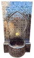 A Moorish-style mosaic fountain wall and basin made of reflective silver mirror tiles, with a small gold circular accent in the center and a visible &