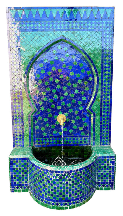 A Moorish-style mosaic tile fountain with a blue and green tiled arch, star pattern, and curved basin. A small gold-toned spout at the top releases a stream of water into the basin.
