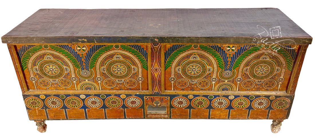 An antique wooden chest or trunk with ornate hand-painted geometric and floral patterns in gold, green, blue, and red on a dark brown wood base, shown against a plain white background.
