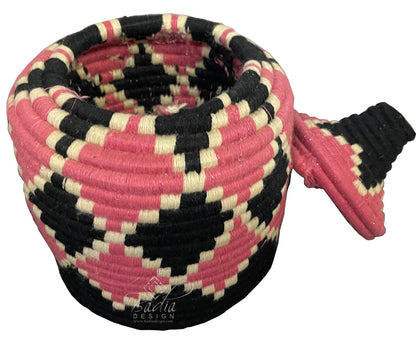 Woven basket with pink, black, and beige pattern on a white background