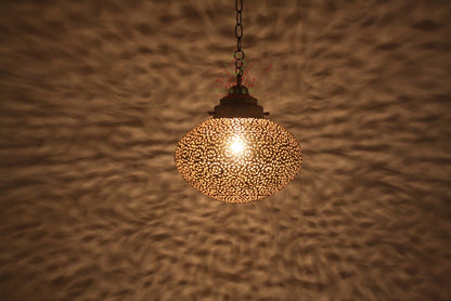Decorative pendant light with intricate design on a textured wall.