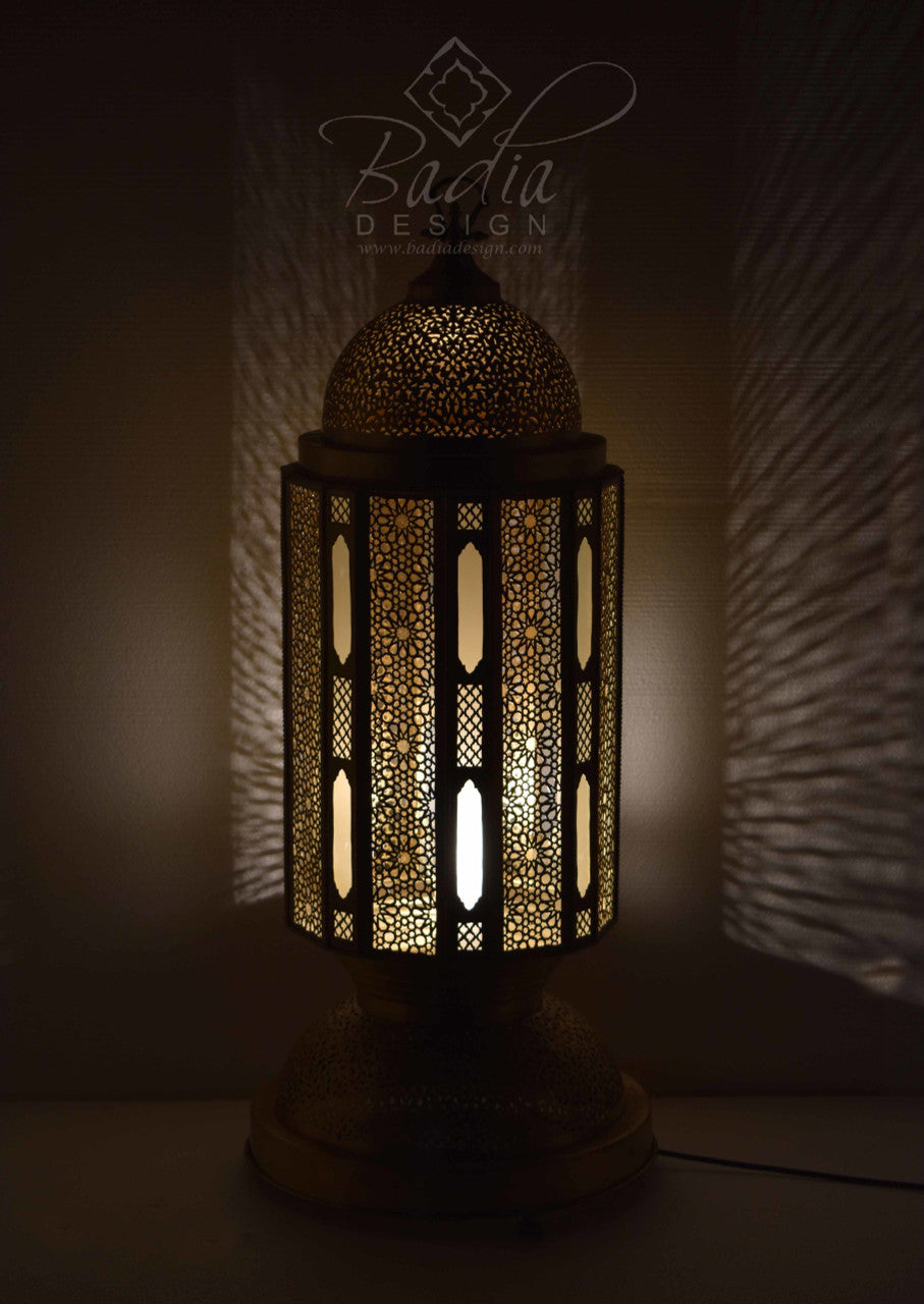 Decorative lamp with intricate patterns, illuminated in a dark setting, featuring the Badia Design logo.