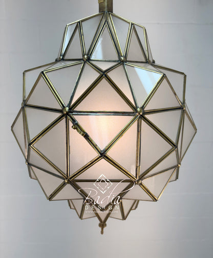Geometric glass pendant light with brass frame on a plain background