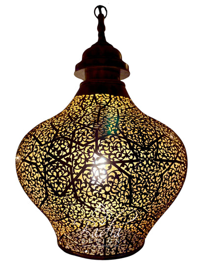 A Moroccan-style hanging pendant lamp with a dark metal frame featuring intricate cutout floral and geometric patterns, illuminated from within to cast a warm golden glow against a white background.