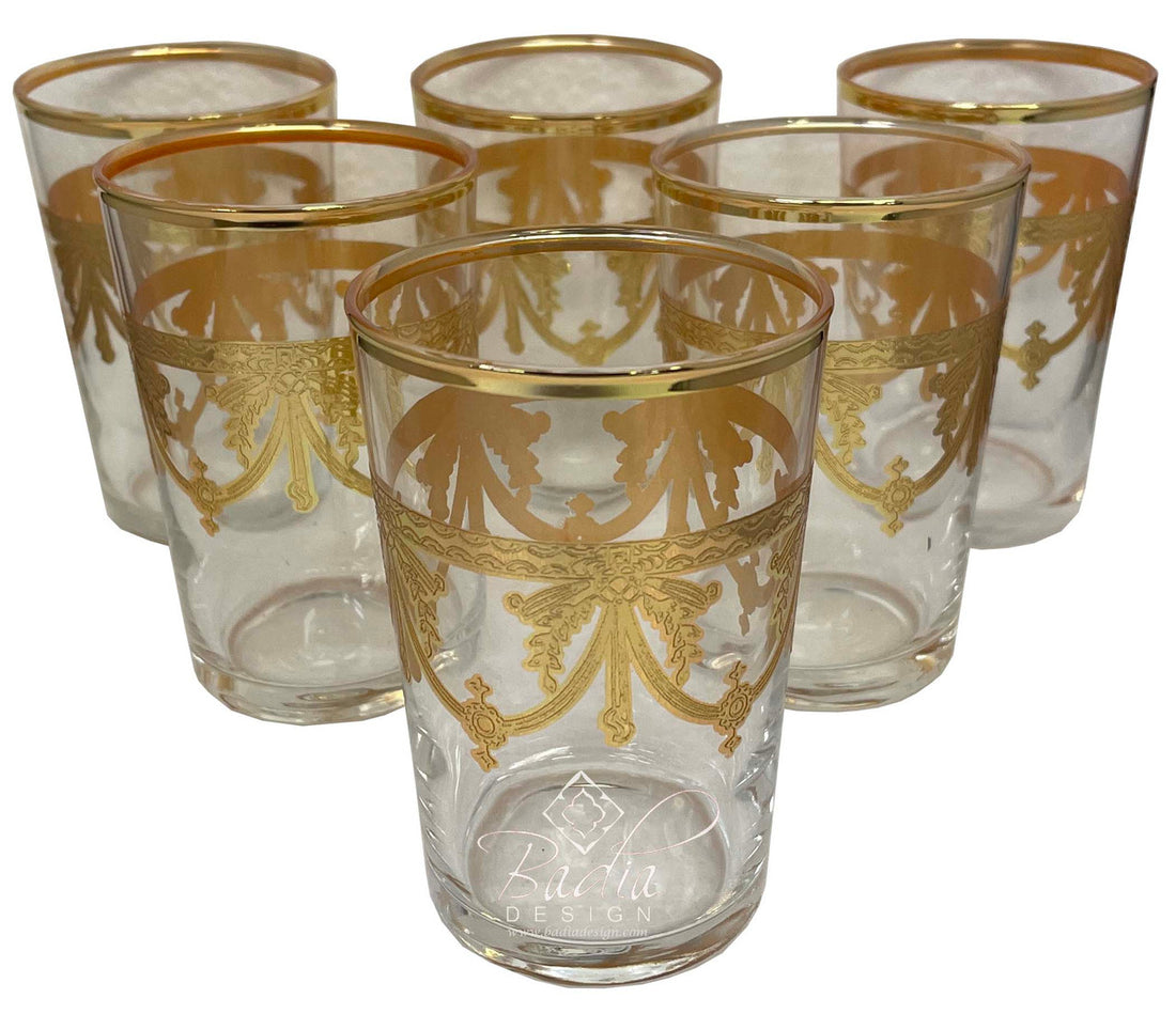 Set of six clear glasses with gold decorative patterns on a white background