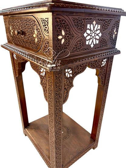 An ornate carved wooden stand or side table with intricate geometric cutouts, a single drawer, and a lower shelf, shown on a plain white background.