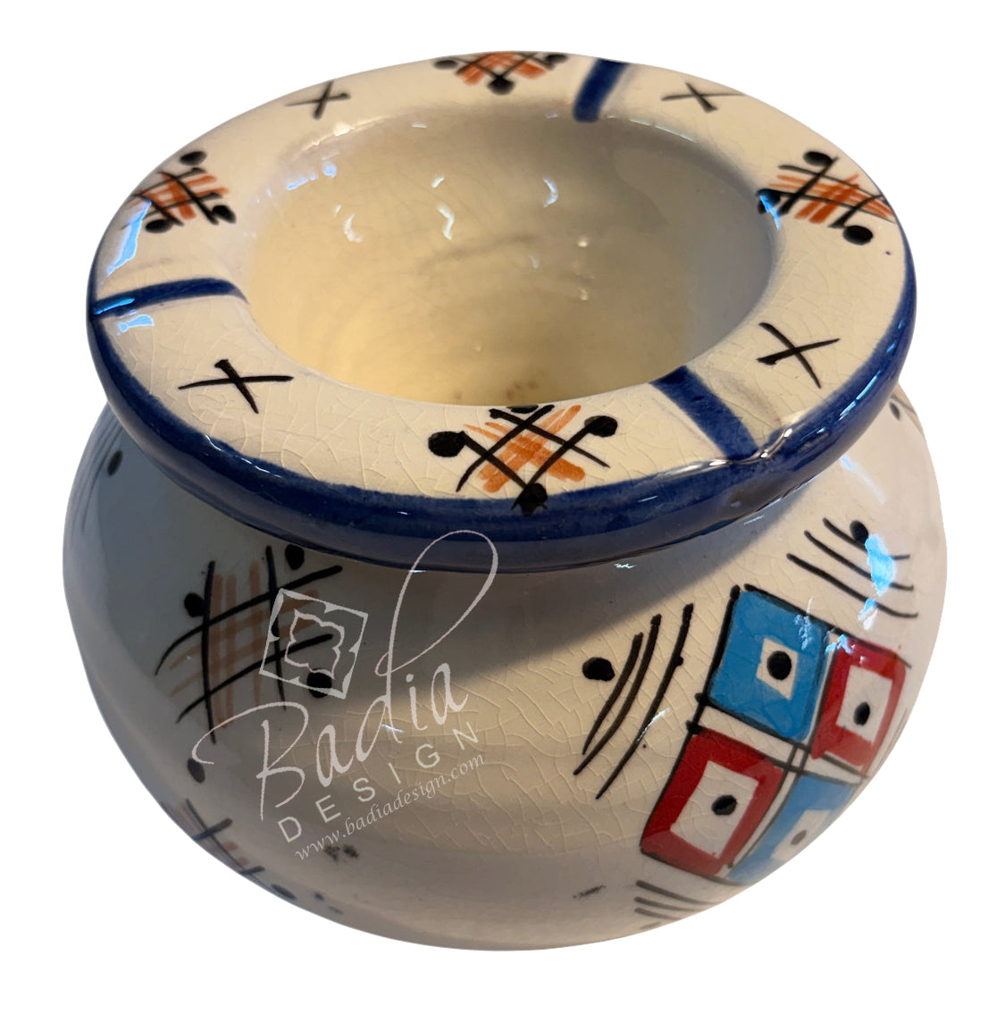 A handmade ceramic pot with a cream-colored glaze, decorated with hand-painted geometric patterns in blue, black, orange, red, and white. A semi-transparent watermark for &
