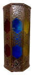 A hexagonal Moroccan-style metal lantern with intricate cutout patterns and colorful stained glass panels in blue, red, and gold, shown on a white background with a &