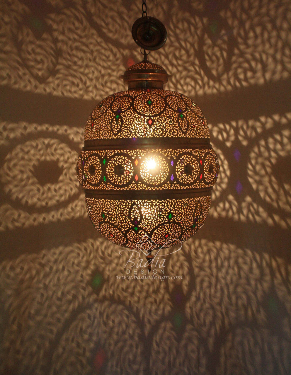Decorative hanging lamp with intricate patterns on a textured wall.