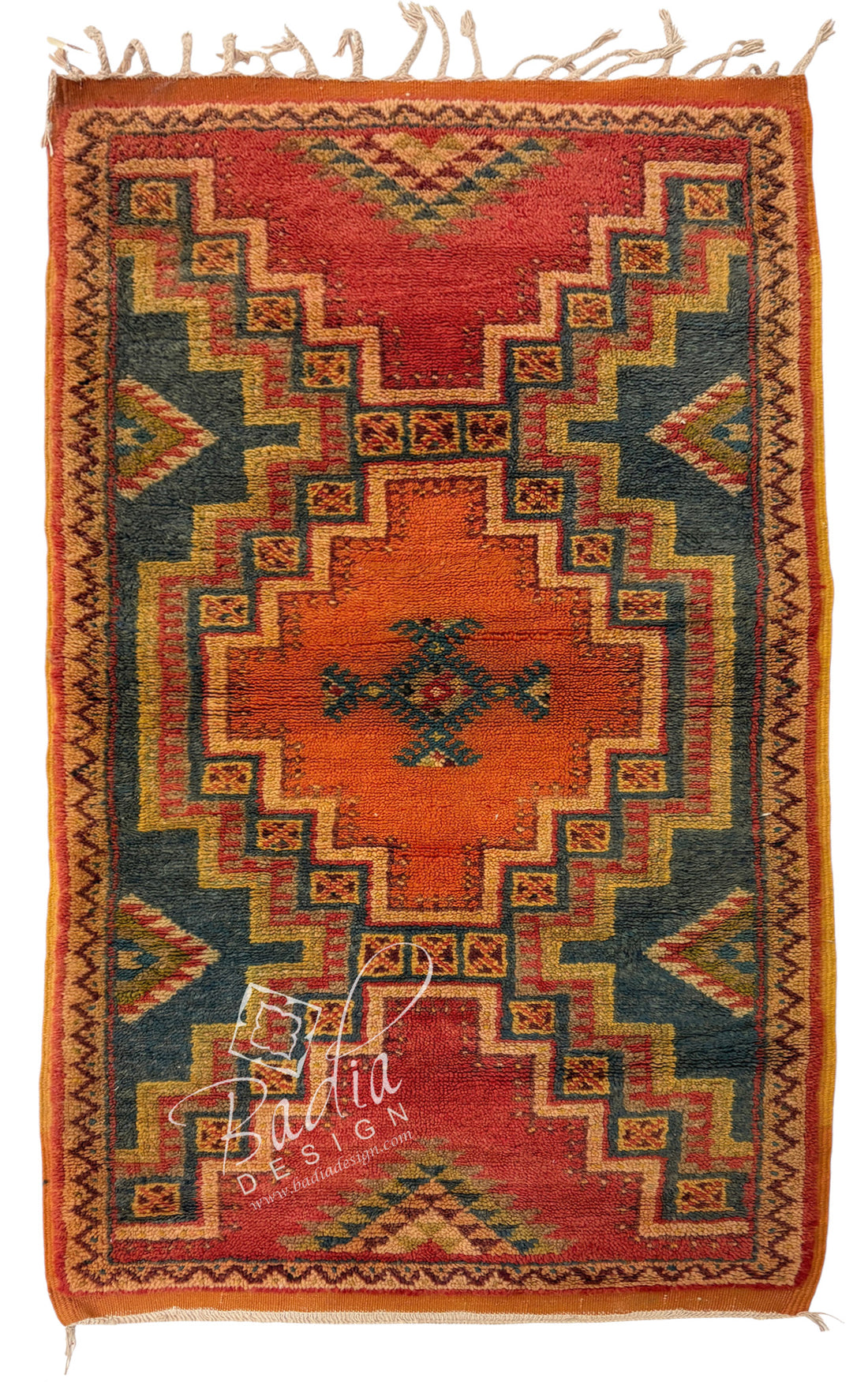 A square vintage-style kilim rug with a geometric pattern in red, orange, green, and beige, featuring a central medallion and fringe on the top and bottom edges.