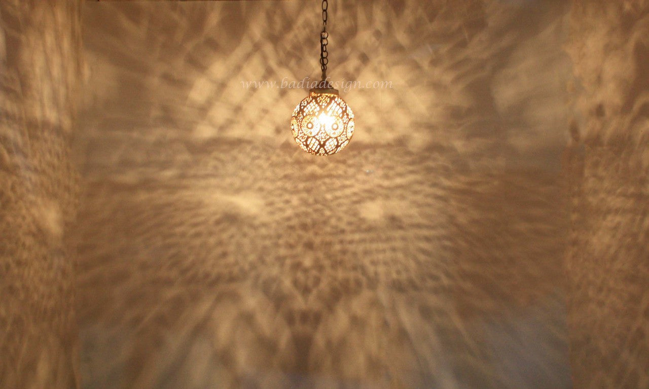 Decorative hanging light fixture casting a pattern on a textured wall.