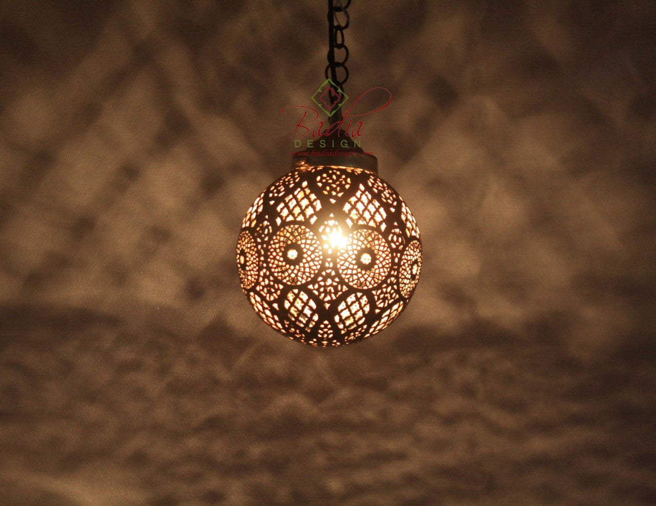 Decorative pendant light with intricate design on a textured wall background