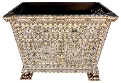 An ornate rectangular cabinet with a black top and legs, covered in intricate mother-of-pearl and gold inlay patterns, shown on a white background.