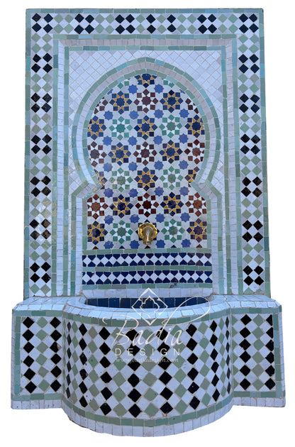 A Moorish-style mosaic fountain wall and basin with geometric tile patterns in white, green, black, blue, and brown, plus a small gold-toned spout detail, shown against a plain white background.