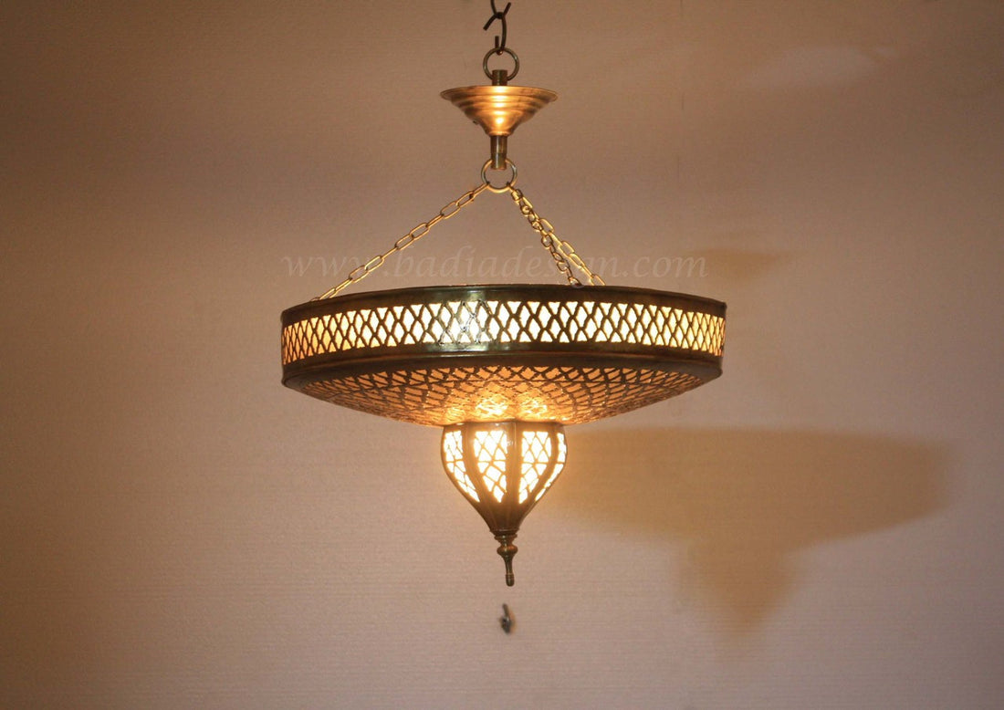 Decorative hanging light fixture with intricate design on a plain wall.
