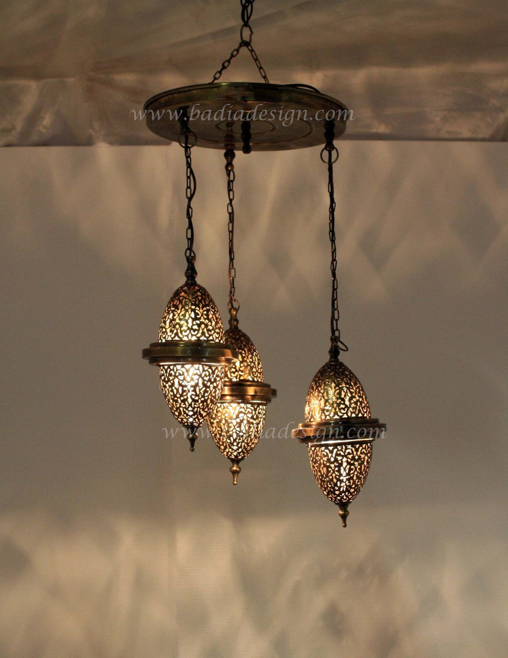 Ornate pendant light fixture with three hanging lights against a neutral background