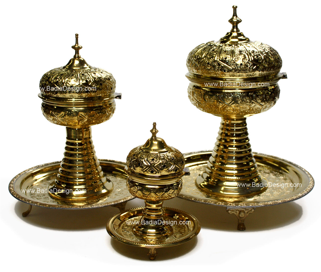 Set of three ornate brass containers on a white background