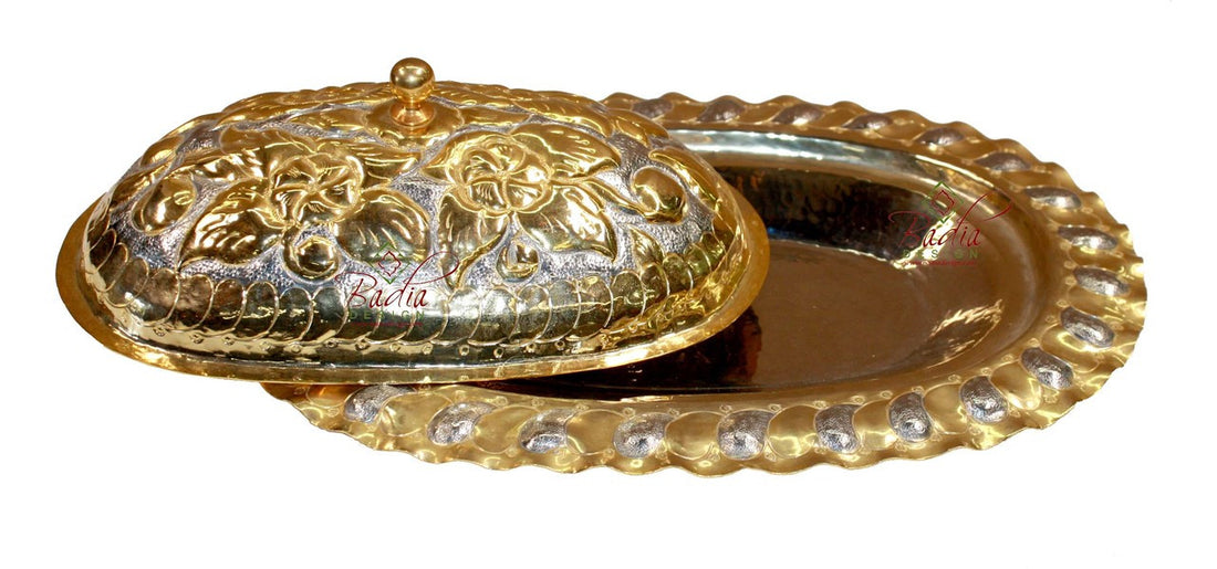 Decorative gold and silver dish with intricate patterns on a white background