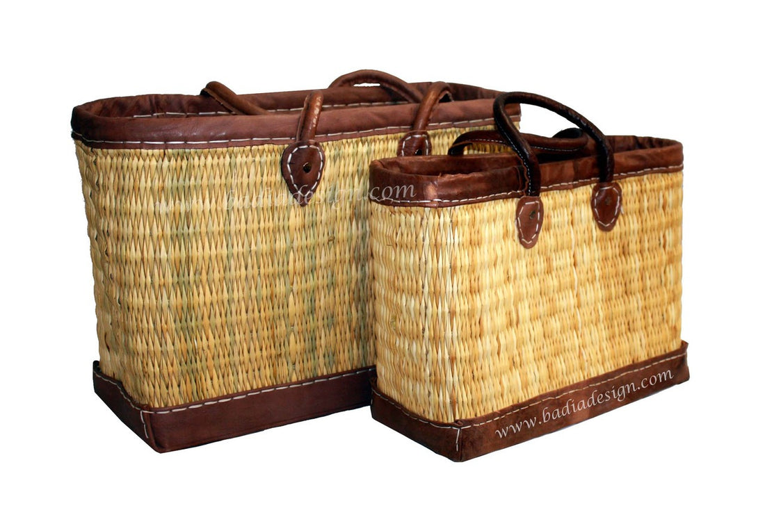 Two woven baskets with brown leather trim on a white background