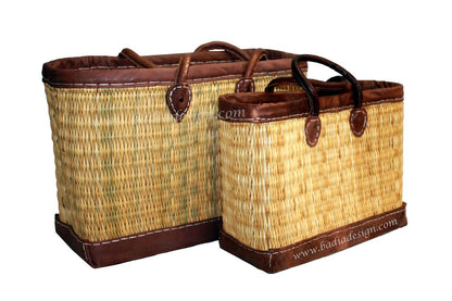 Two woven baskets with brown leather trim on a white background