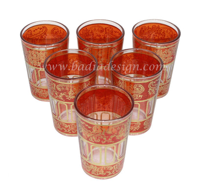 Set of six red glass tea cups with gold patterns on a white background