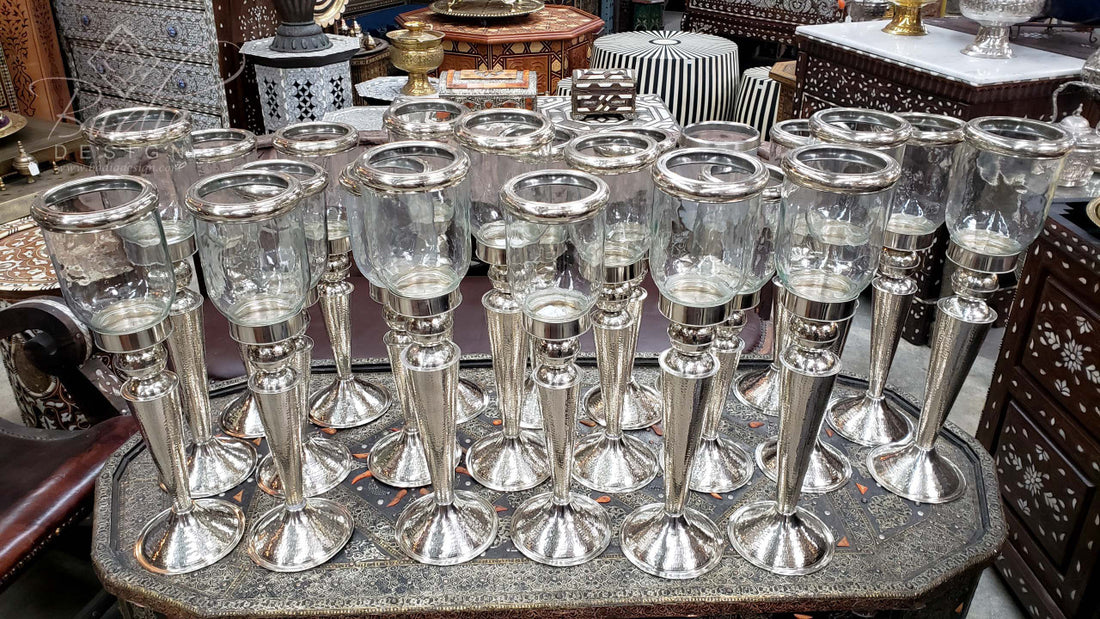 Collection of silver candle holders on a stone surface with a blurred background