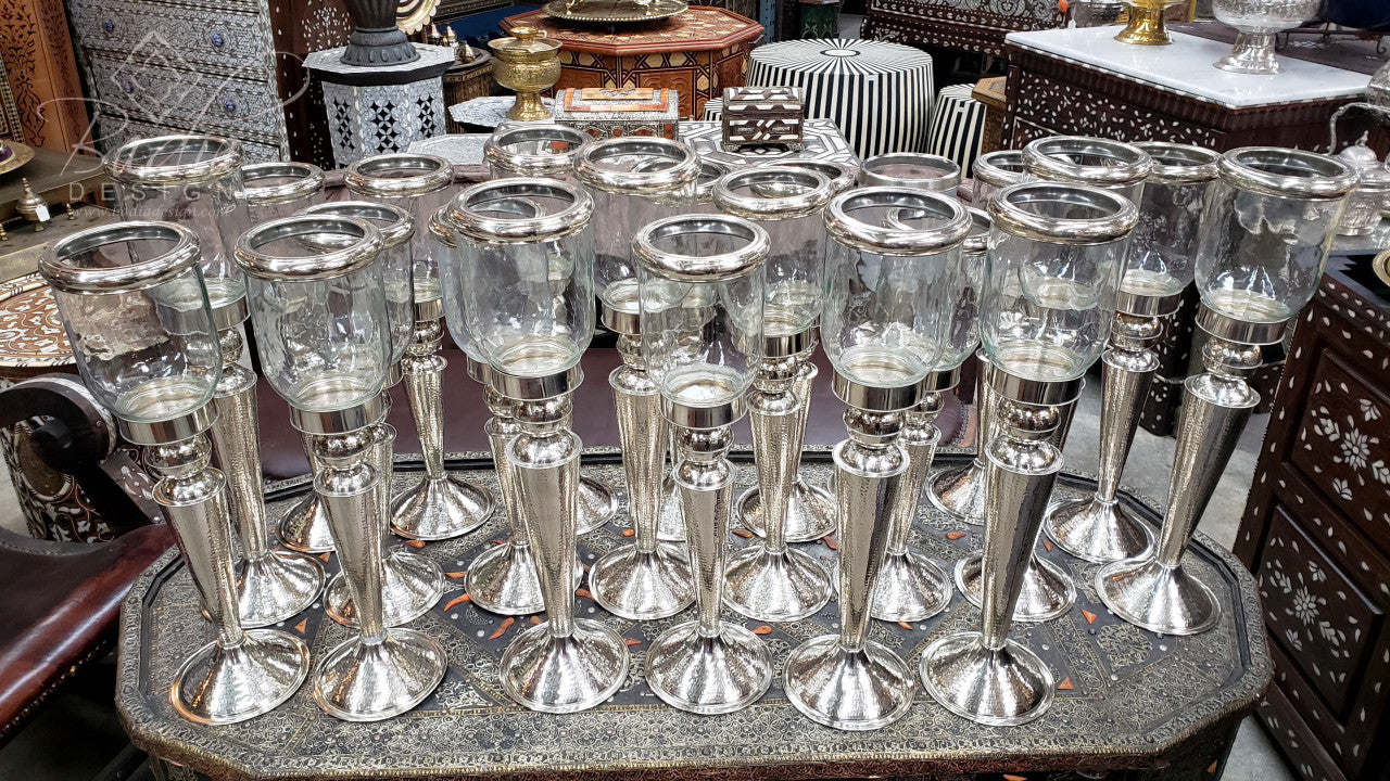 Collection of silver candle holders on a stone surface with a blurred background