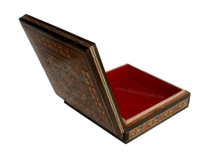 Decorative wooden box with intricate patterns and a red interior on a white background.