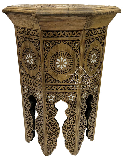 Decorative wooden side table with intricate carvings on a white background